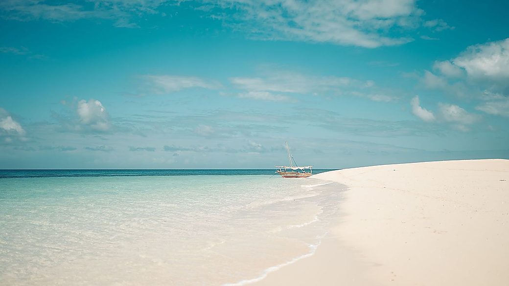 A dhow moored on a turquoise sandbank
